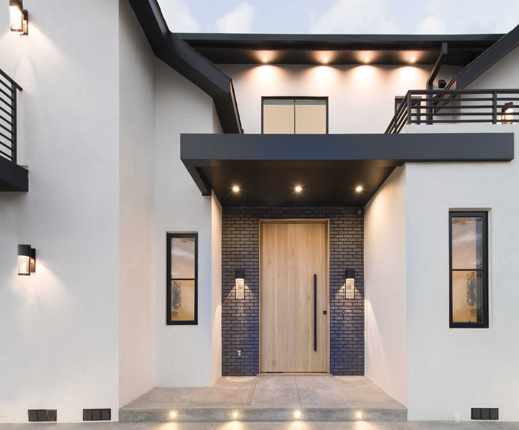 Entry detail with blue brick surround and warm oak pivot door