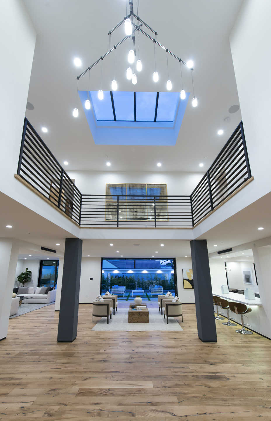 Double-height great room with skylight, custom chandelier, and oak floors