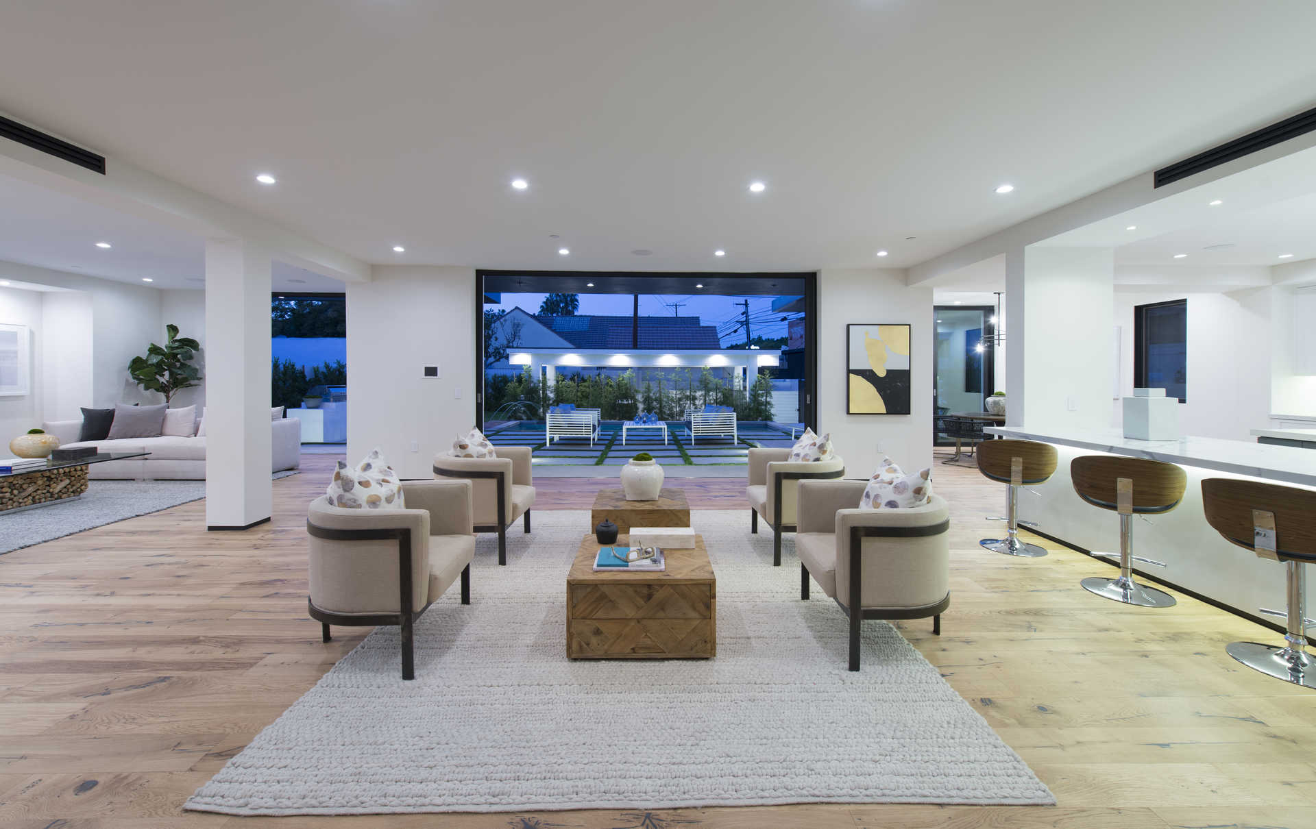 Open lounge area with kitchen bar seating and view through to the pool