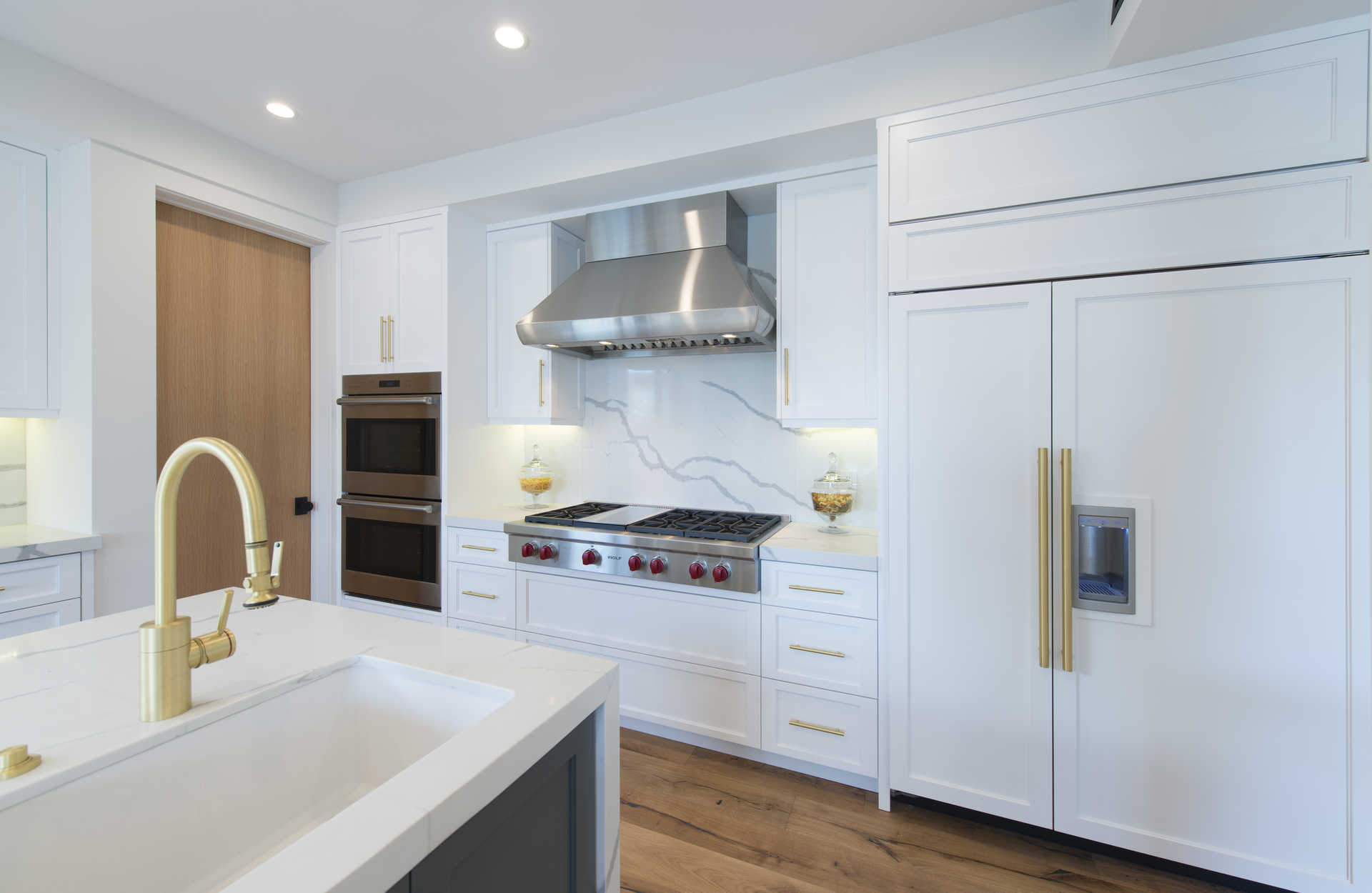 Kitchen detail with Wolf range, marble backsplash, and integrated paneled appliances