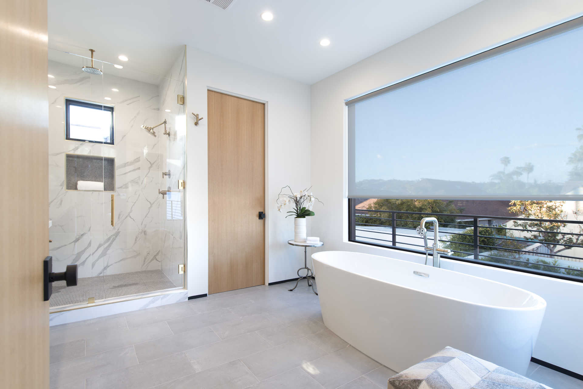 Primary bath with freestanding tub, marble shower, and brass fixtures