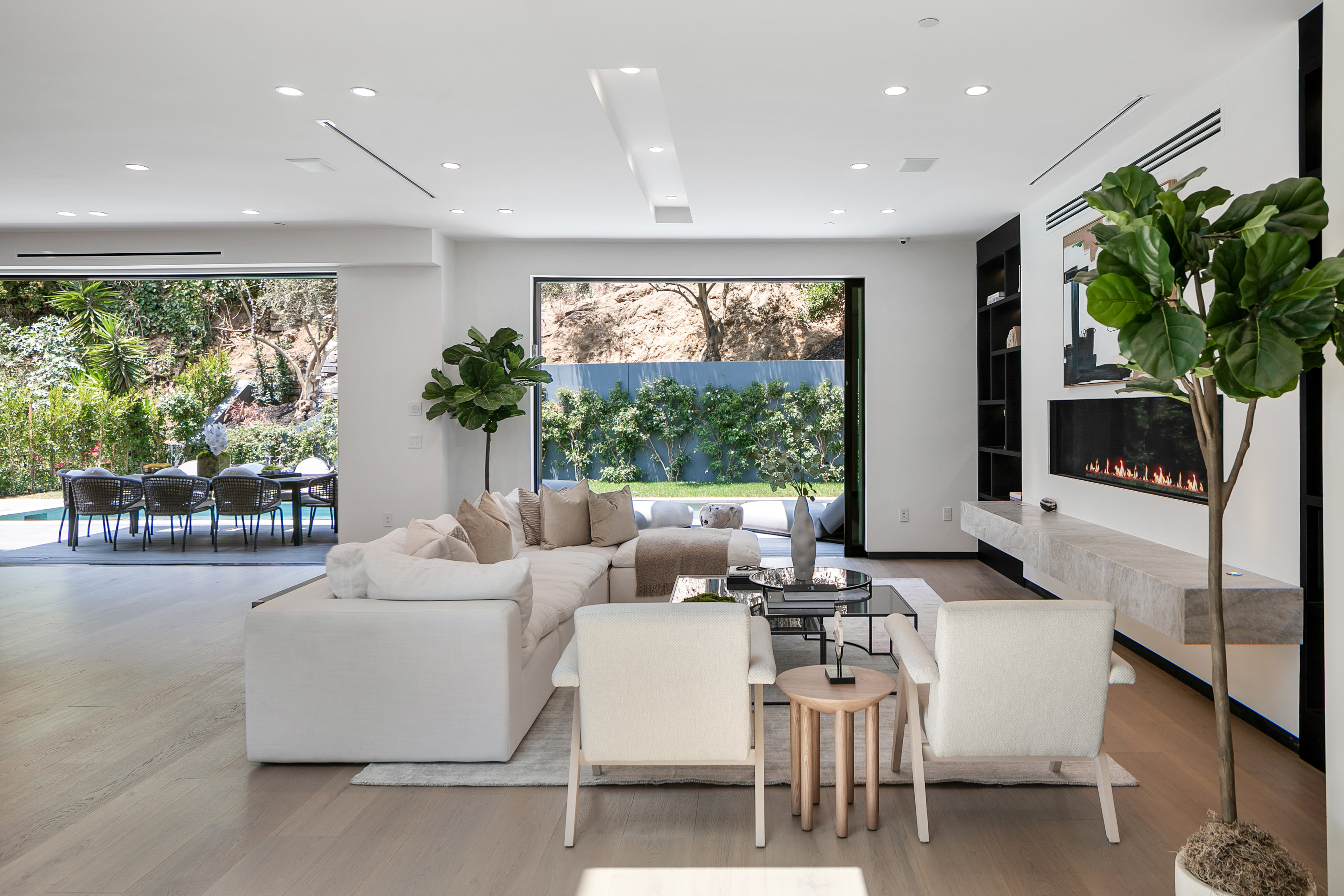 Living room dissolving to pool terrace through sliding glass walls