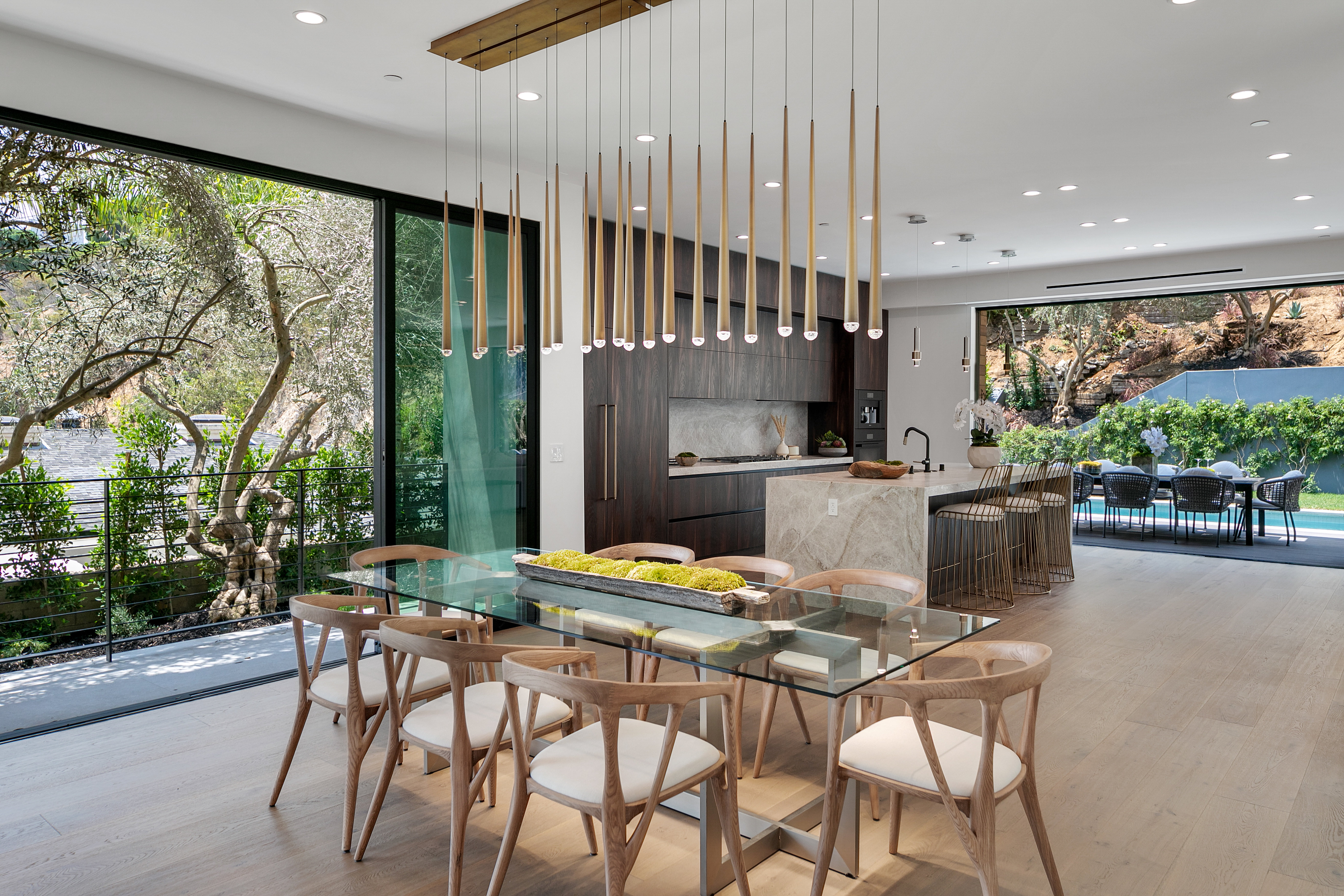 Glass dining table beneath vertical pendant rain